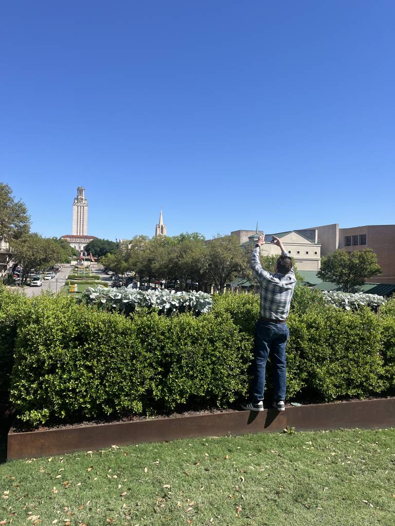 Man photographing UT tower from a distance