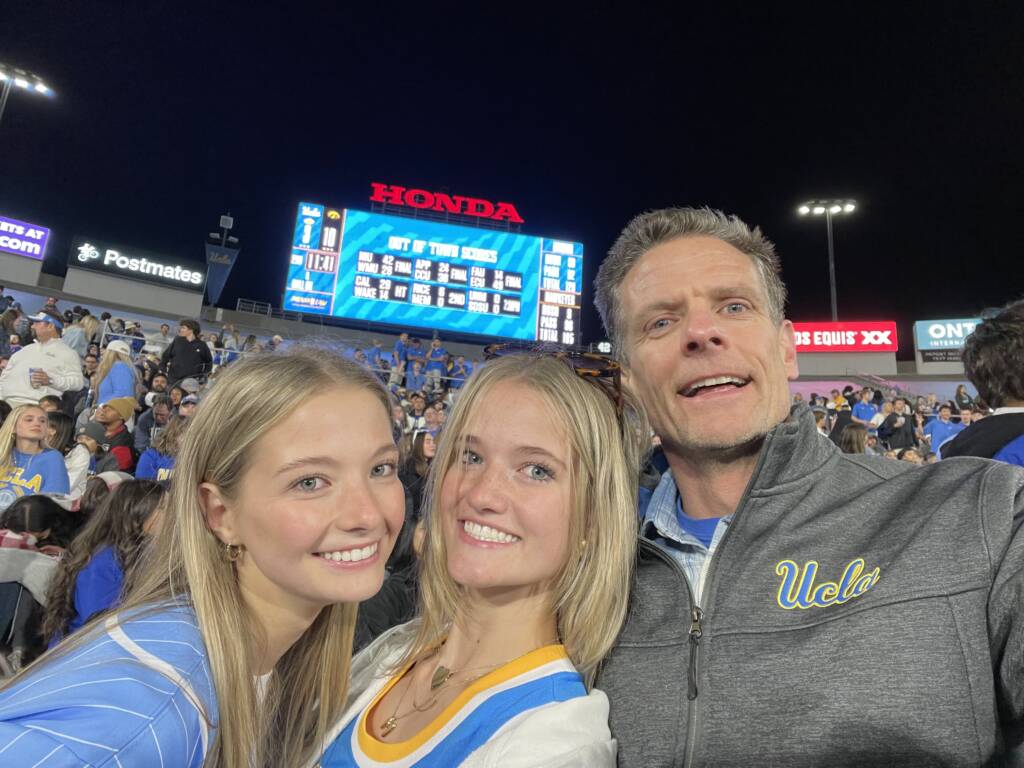 A view of the scoreboard and three people at the Rose Bowl during a football game